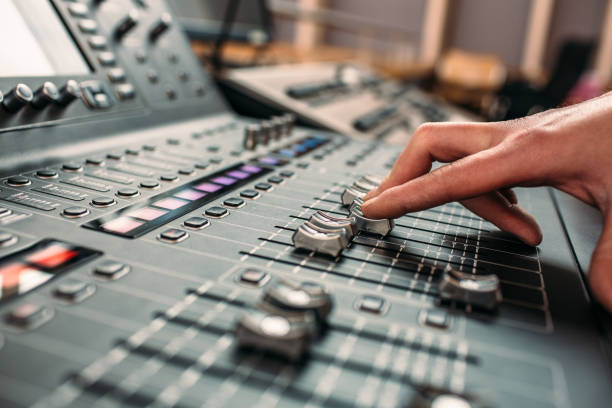 A person's hand moving sliders on a professional high end sound mixing desk.