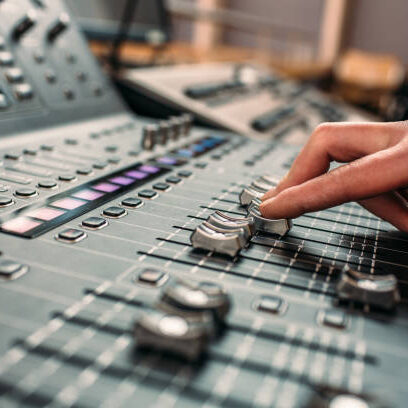 A person's hand moving sliders on a professional high end sound mixing desk.